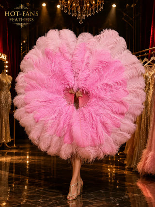 Oversized blush pink and soft pink ostrich feather fan in a luxury HOT-FANS stage-inspired promotional scene, held in an elegant side pose.